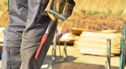 Close up of builder with hammer hanging off belt