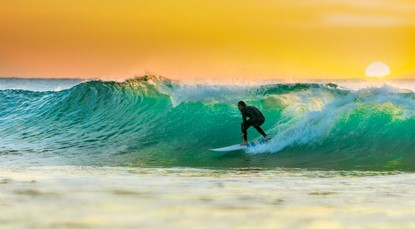 Person surfing, yellow sky