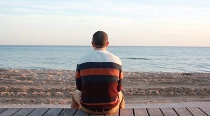 Back of man sitting, looking towards the horizon