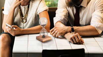 Couple sitting at table with hour glass