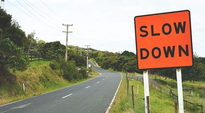 'Slow down' sign next to rural road