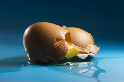 Broken egg sitting on blue surface