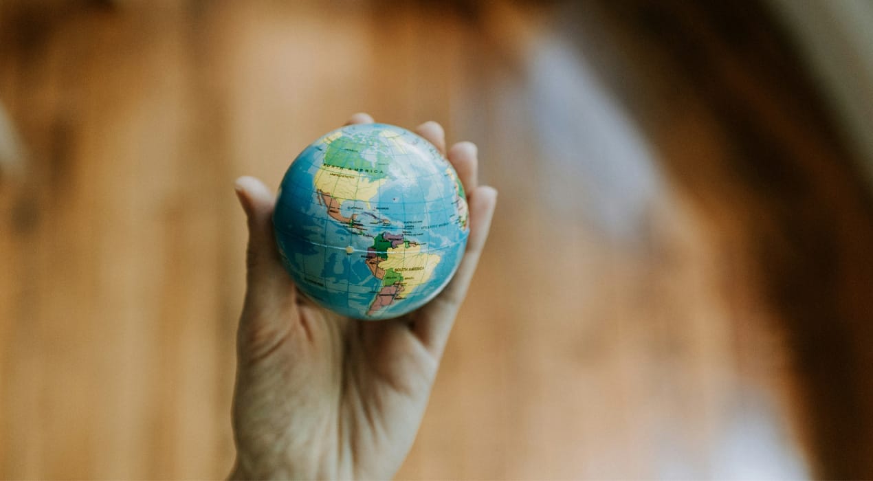 Close up image of a hand holding a small globe