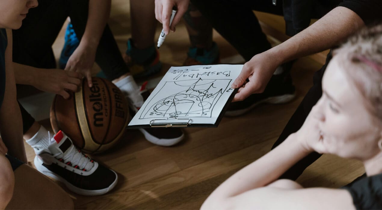 Basketball coach talking players through a roughly drawn game plan