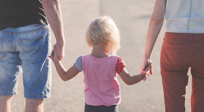 Couple walking hand in hand with their little girl