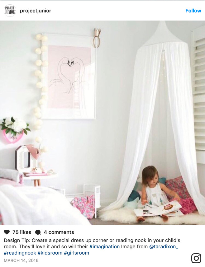 Toddler looking at a book in a reading nook