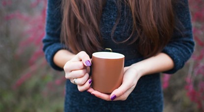 Woman holding warm mug outside