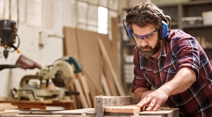 Builder with earphones, sawing
