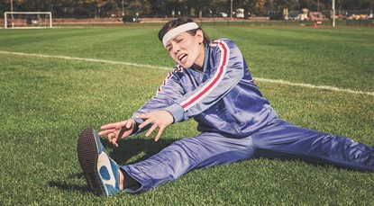Woman trying to stretch on football pitch