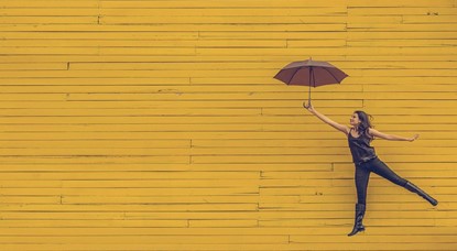 Woman holding umbrella against yellow background