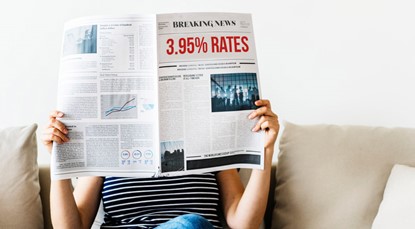 Woman sitting on couch reading newspaper about 3.95% mortgage rates