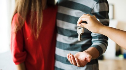 Young couple being handed a key to their brand new home