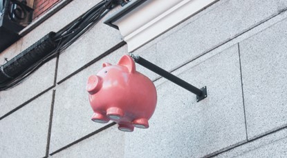 Pink piggy bank hanging off side of the building