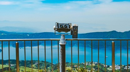 Binoculars next to rail, facing town by an ocean