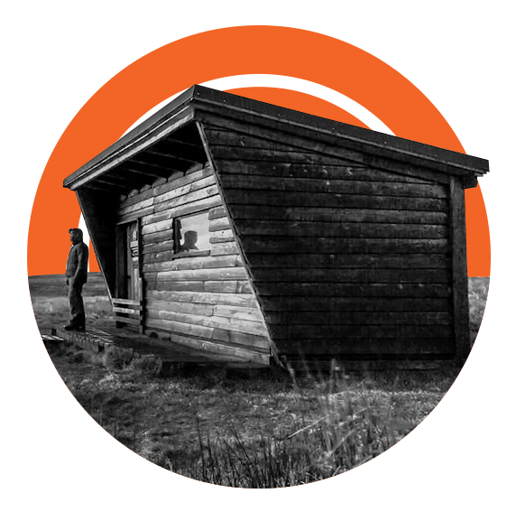 Man standing in front of tiny house on a field