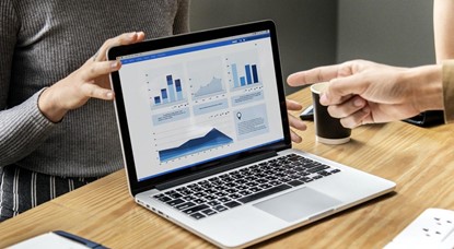 Two peoples' hands pointing to laptop screen with graph