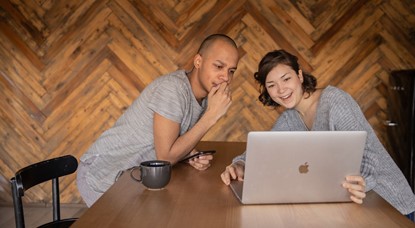 Young guy and woman sitting at table looking at laptop
