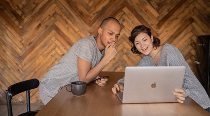 Young guy and woman sitting at table looking at laptop
