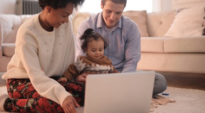 Parents and child sitting in front of laptop on floor