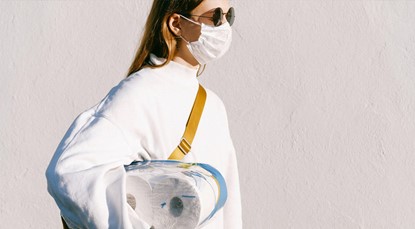Young woman wearing surgical mask, holding toilet paper