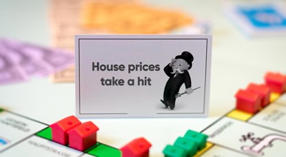 Monopoly board with chance card reading "House prices take a hit"