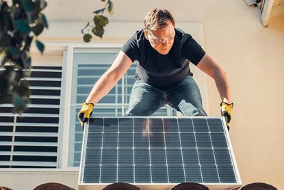 Man installing solar panels on roof of house.