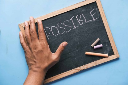 Chalk board reading "Impossible", with hand covering up the "IM" so it now reads "Possible"