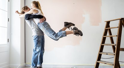 Young couple jumping into each other's arms in a room being renovated