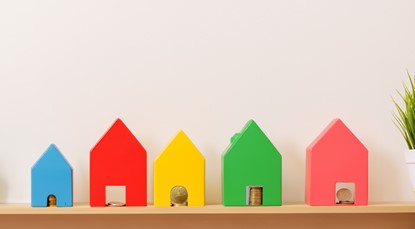 Toy houses with coins, lined up on shelf